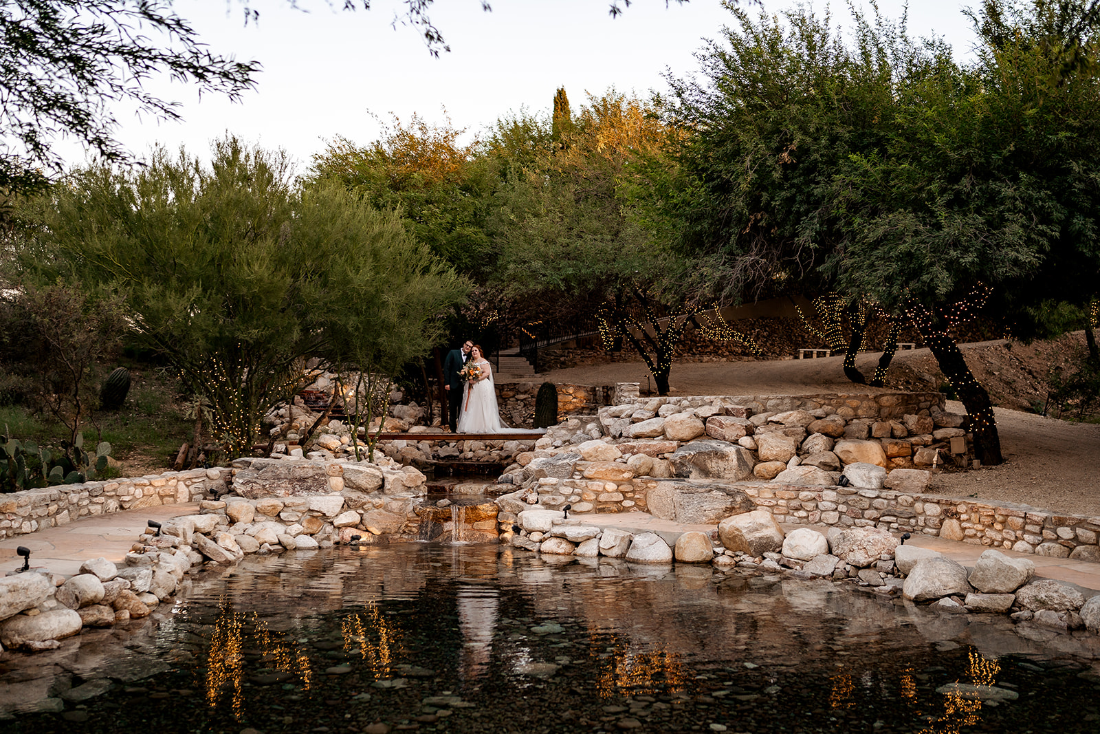 bride and groom posing for wedding photography at saguaro buttes venue pond