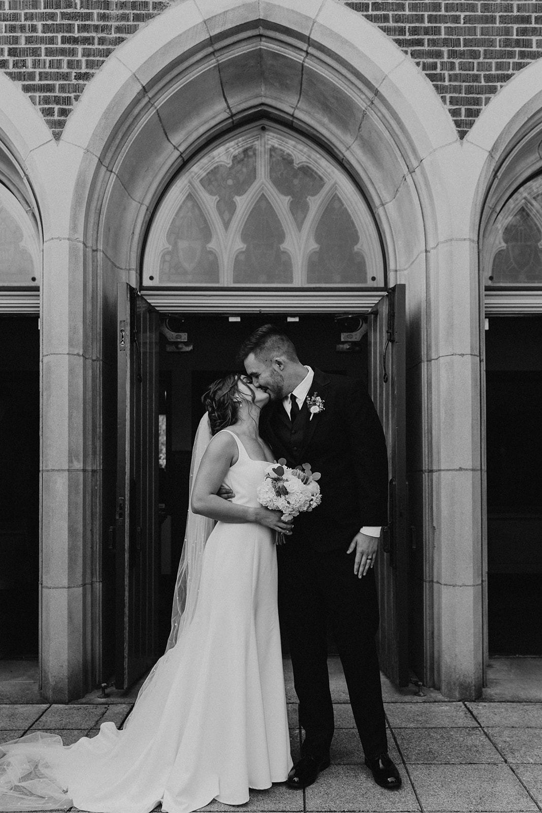 Bride and groom kissing outside of church