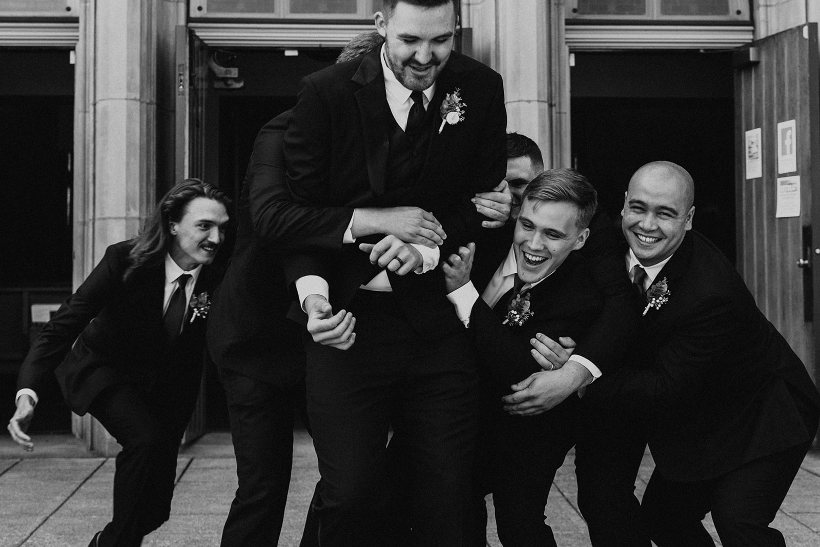 Groom being lifted by his groomsmen