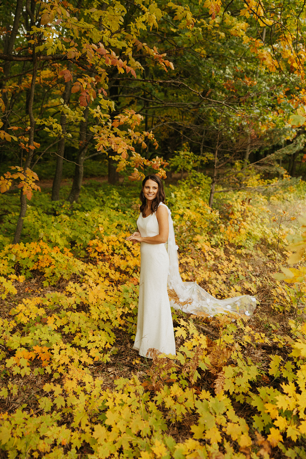 Bride standing in a wide open field with fall leaves and colors all around in West Michigan.