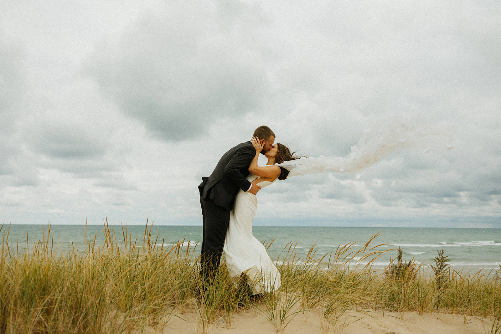 Bride and groom walking on the beach alongside Lake Michigan for their Grand Rapids wedding.