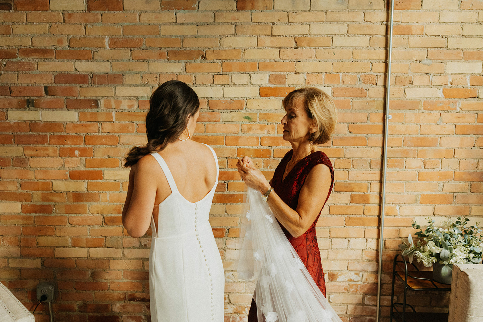 Bride and her mother getting the wedding dress on in the bridal suite in downtown Grand Rapids, Michigan.