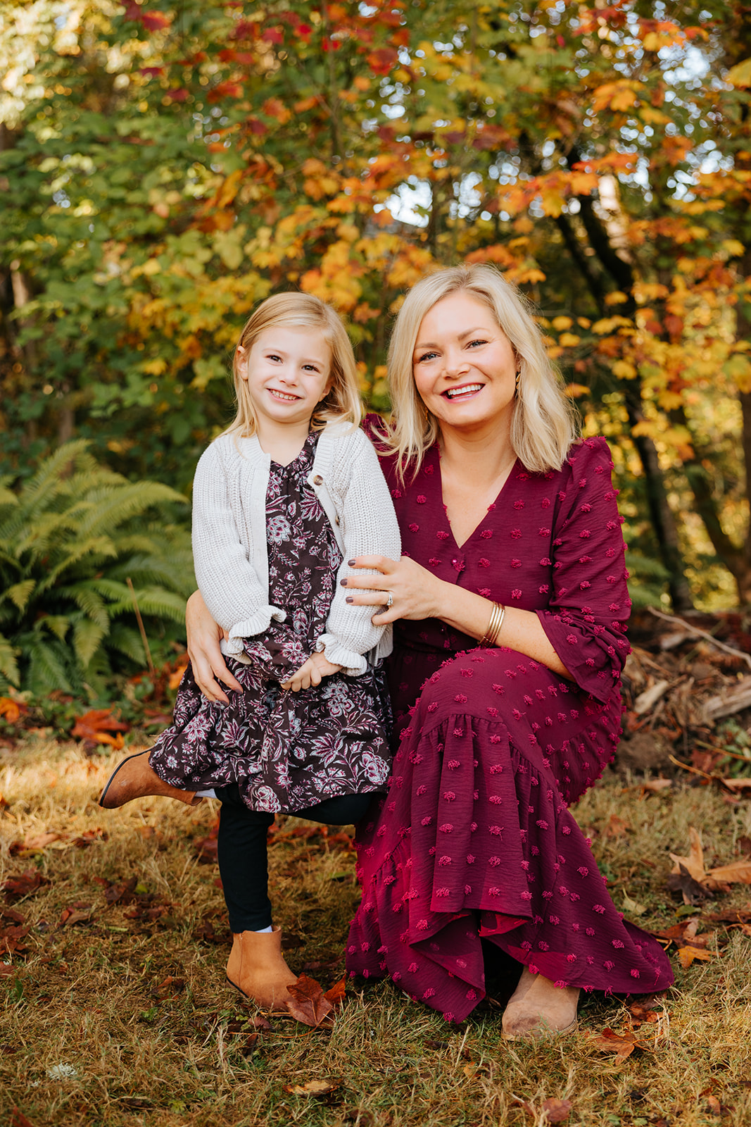 A photo of a mother and daughter smiling for the camera in front of colorful fall foliage at a Seattle park.