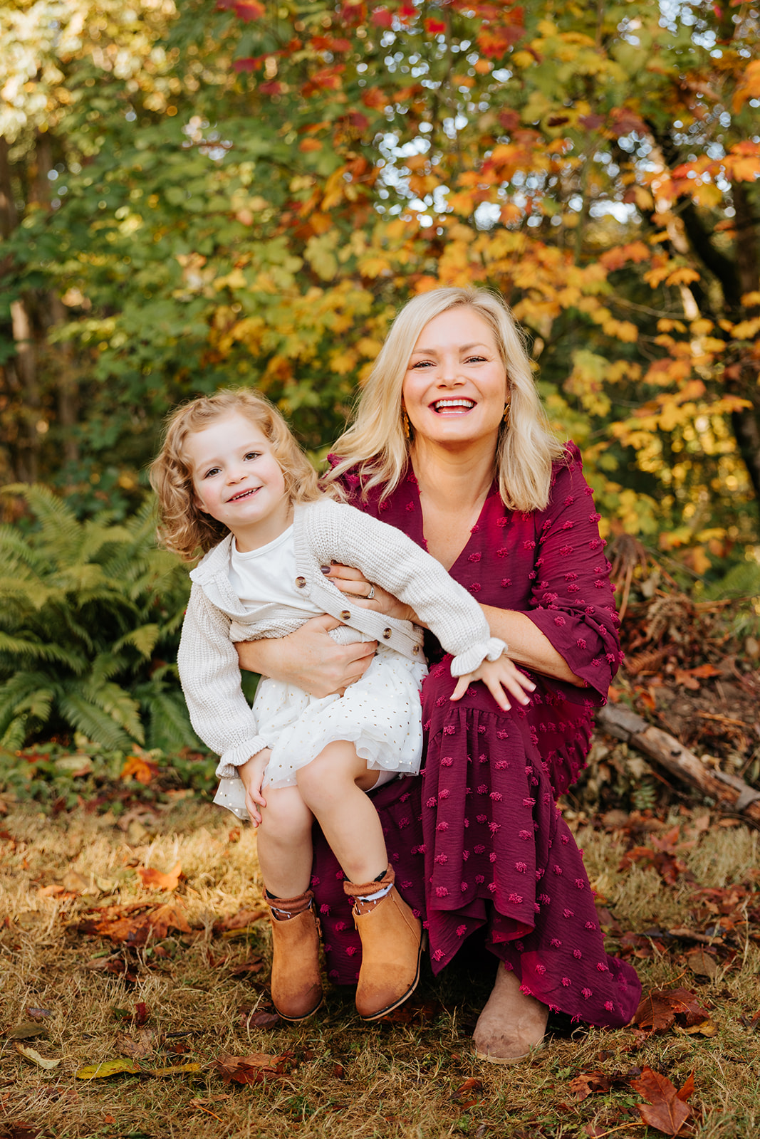 A photo of a mother and daughter smiling for the camera in front of colorful fall foliage at a Seattle park.