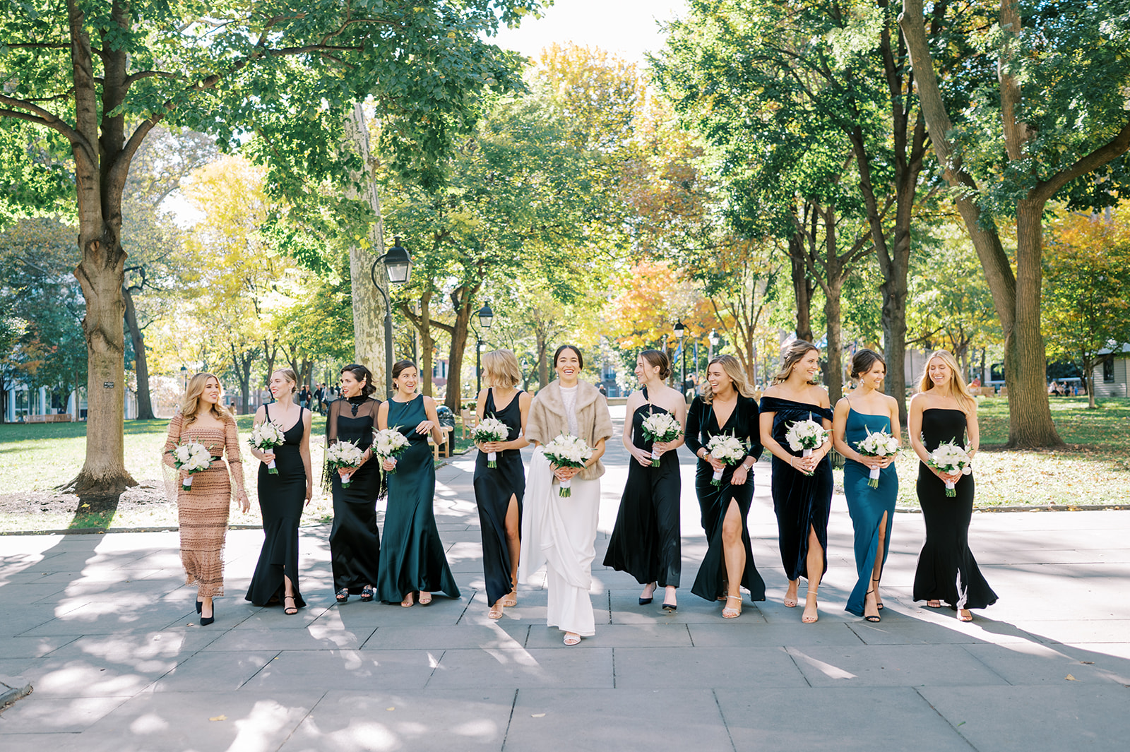 bride with shawl with bridesmaids walking and laughing in washington square park