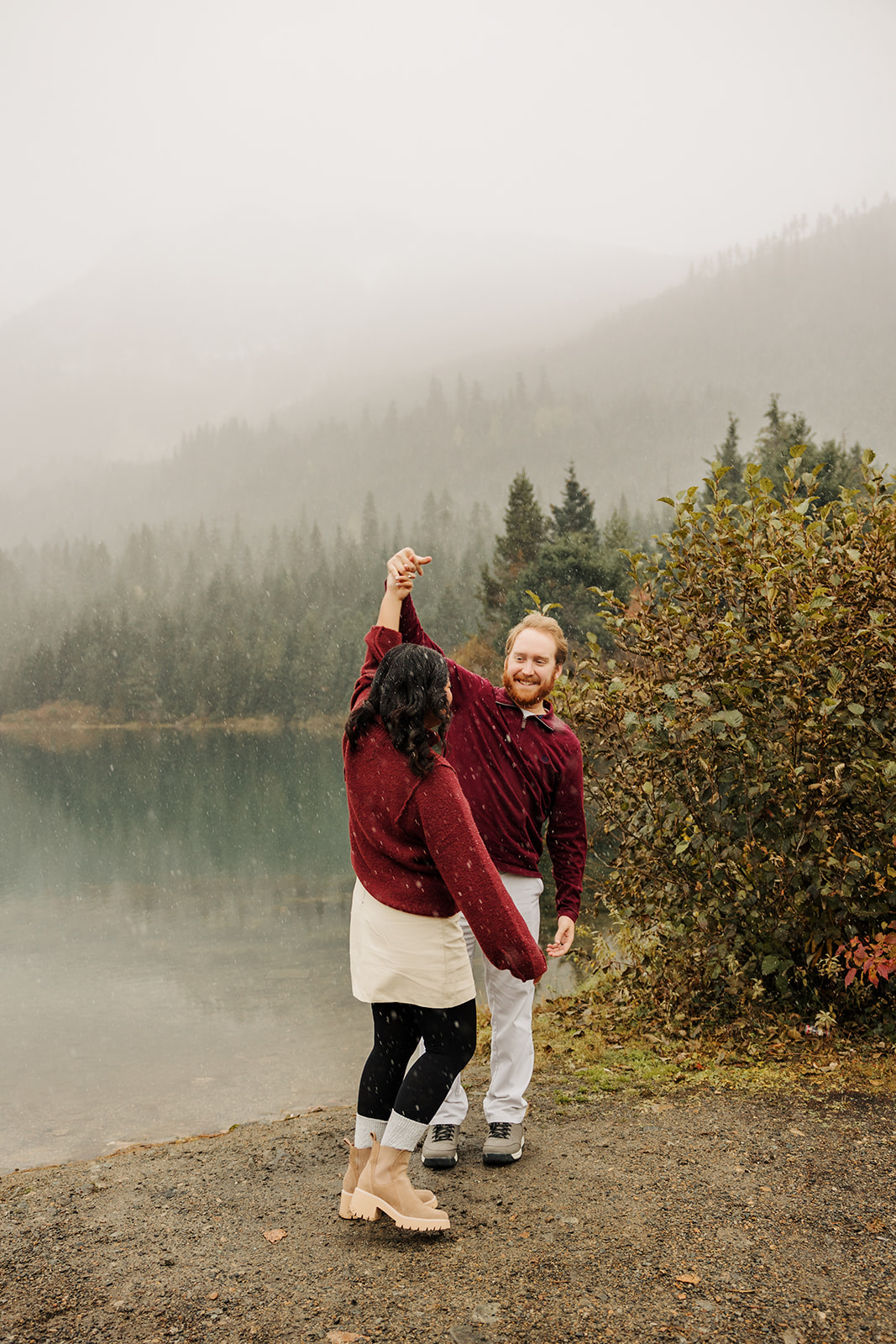 A photo of a loving couple dancing near a winter pond in the mountains of Washington while the snow falls.