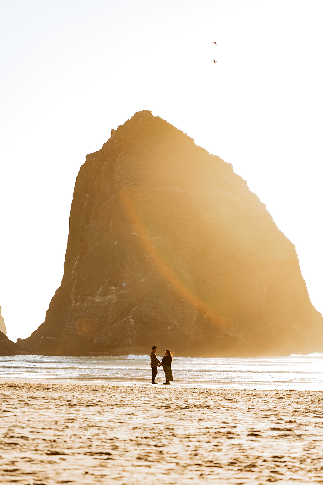 Couple standing in front of Haystack Rock at Cannon Beach
