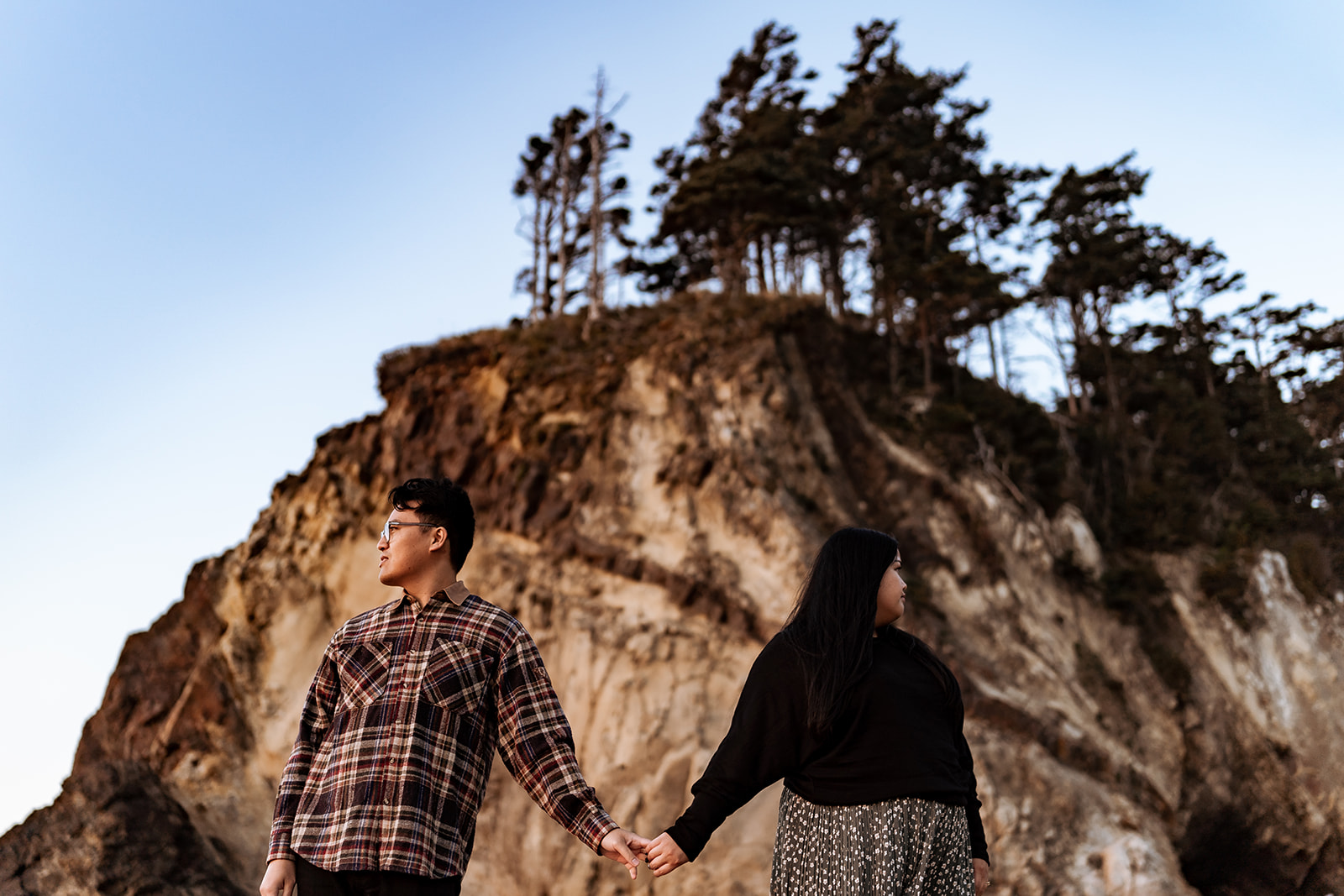 engagement photo of couple holding hands in front of Hug Point caves
