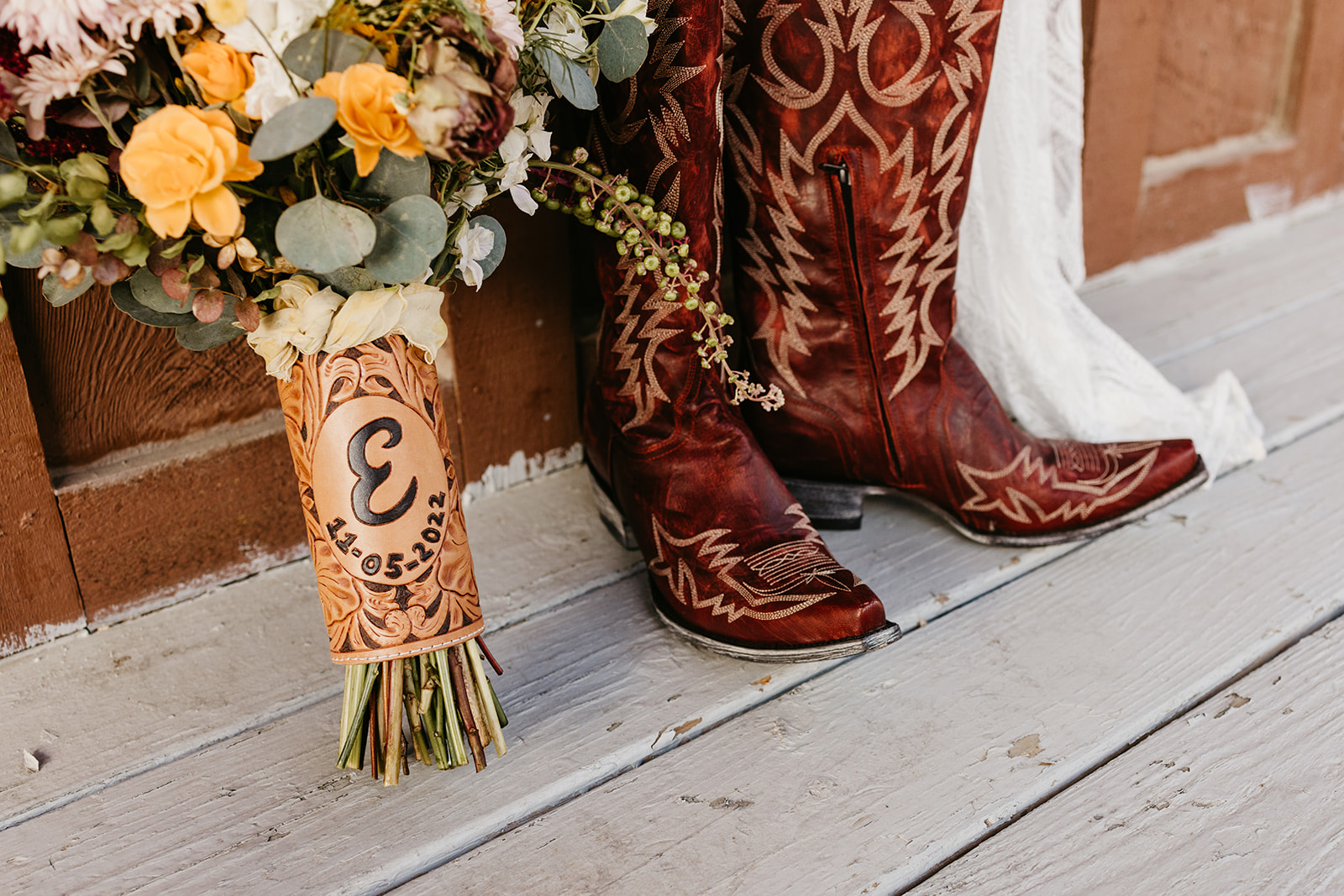 Red cowboy boots next to a boquet with a custom leather wrap