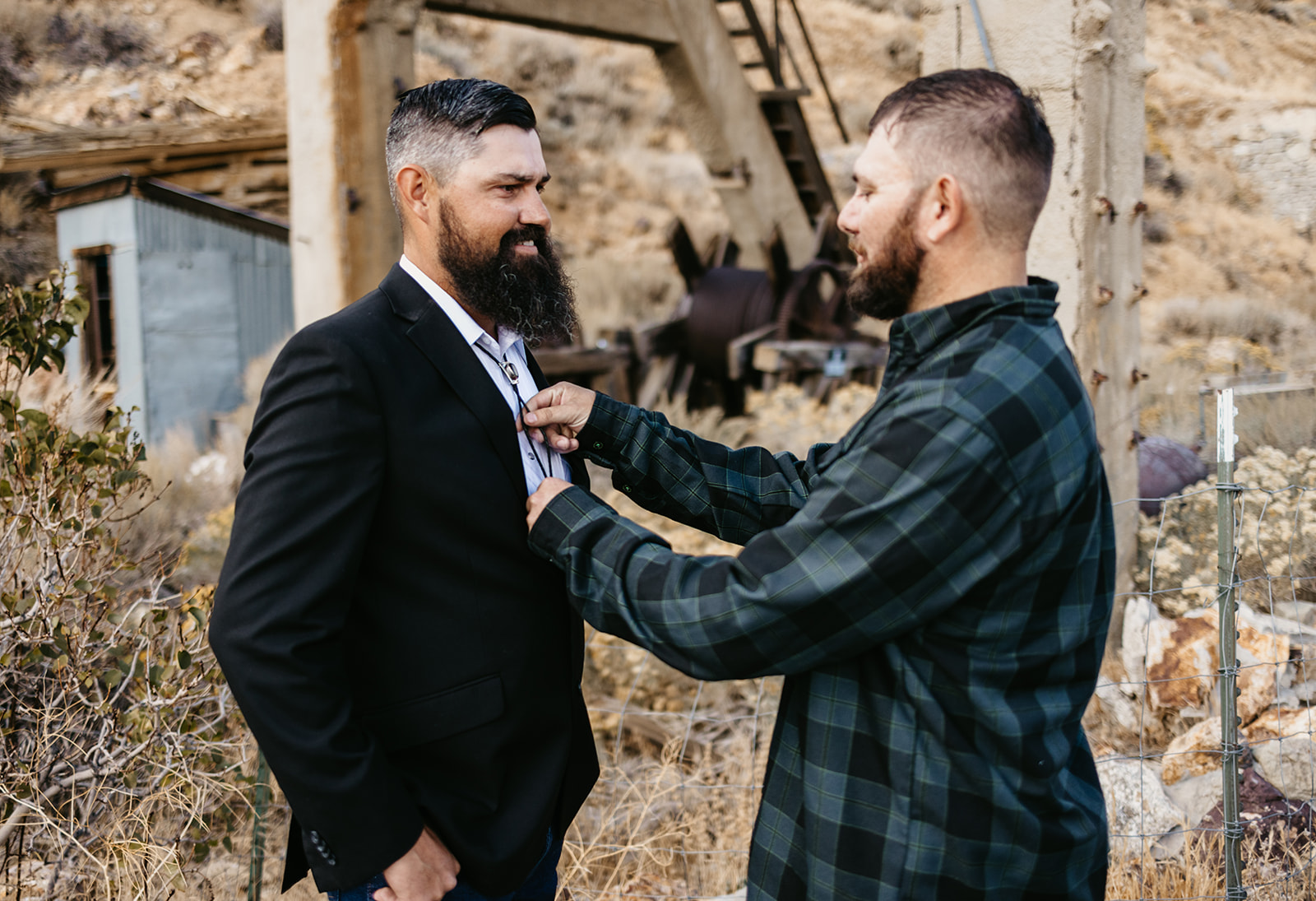 Grooms brother helps him put on his bolo tie