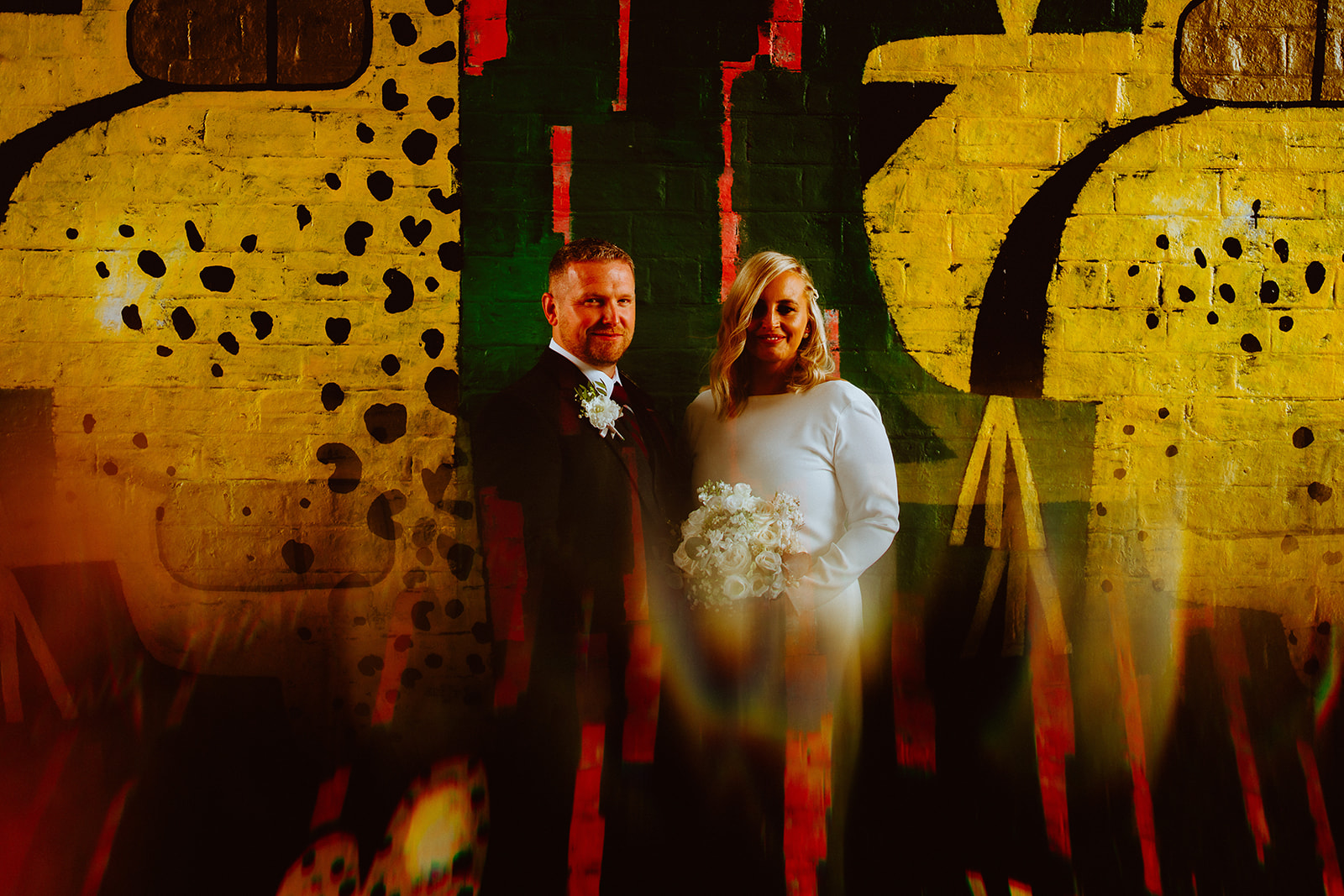 Wedding couple, standing in front of graffiti mural in Glasgow.