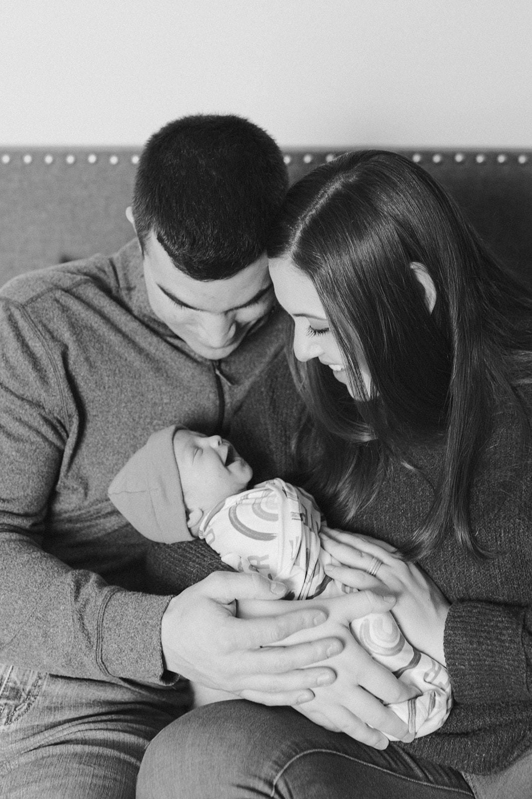 couple holding baby in the nursery during in-home newborn family photo session. 