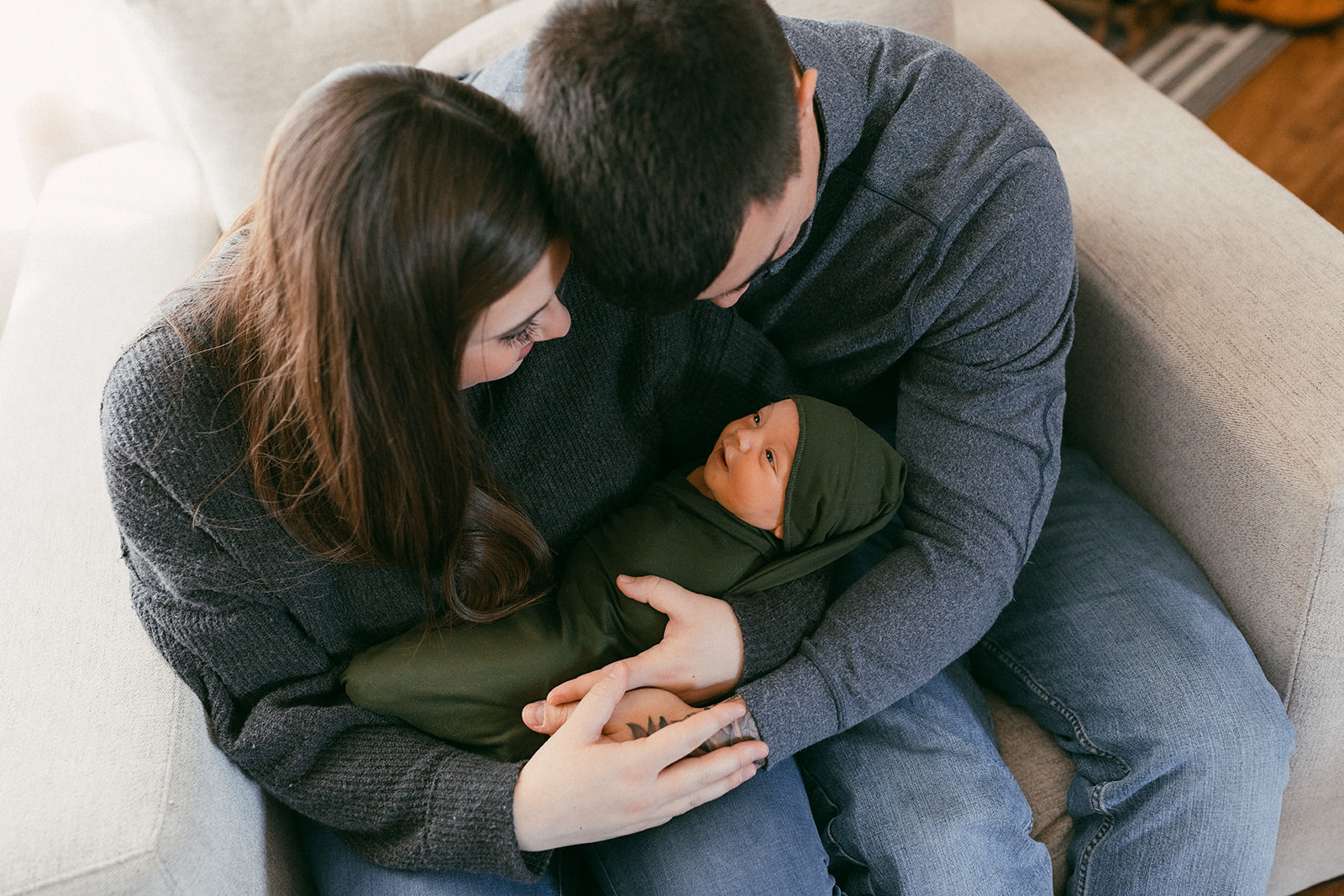 couple holding baby in the nursery during in-home newborn family photo session. 