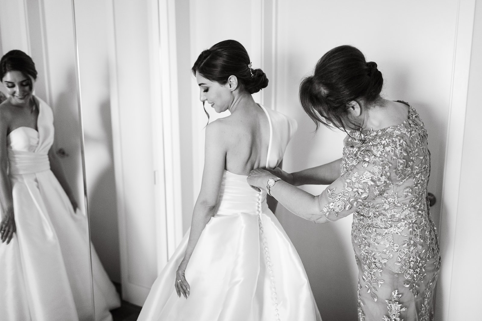 a mother helping a bride into her wedding dress