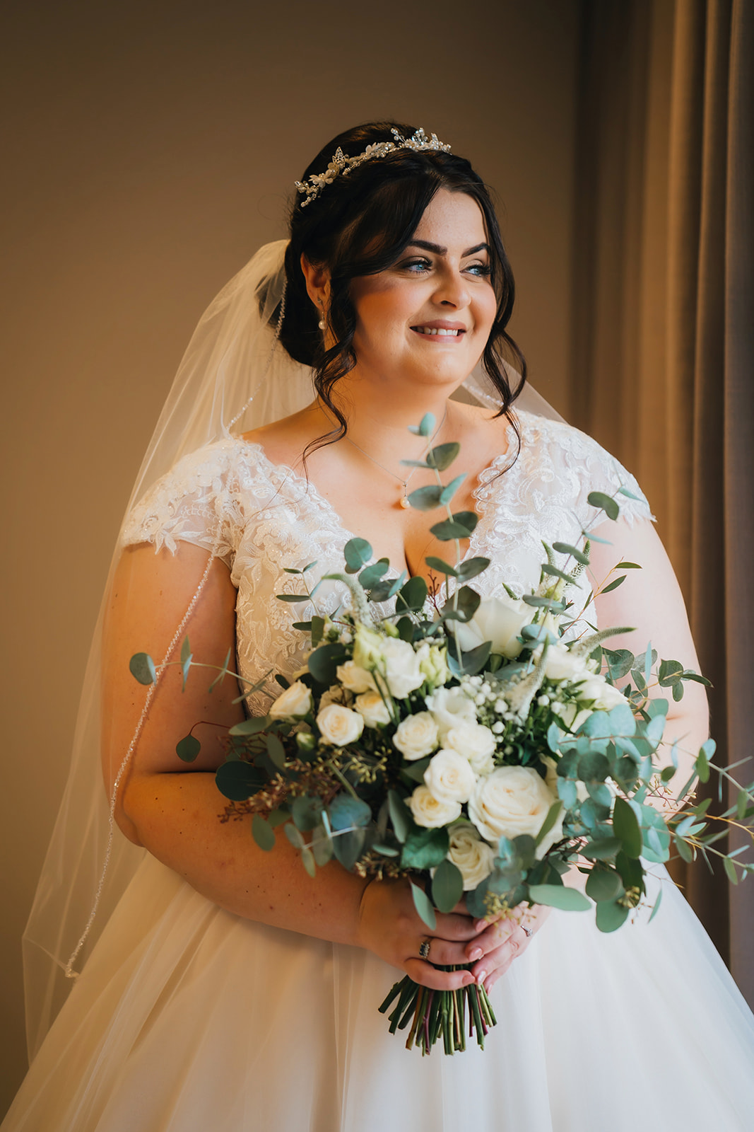 A bridal portrait with side window light. The bride holds her bouquet