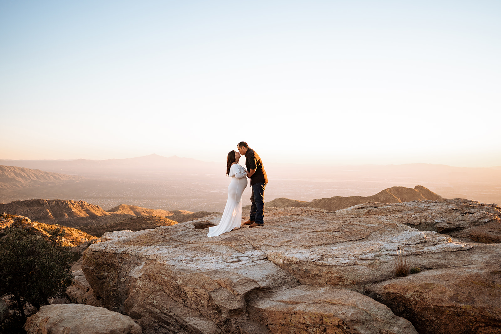 a couple posing for maternity photos at Windy Point at Mount Lemmon during sunset