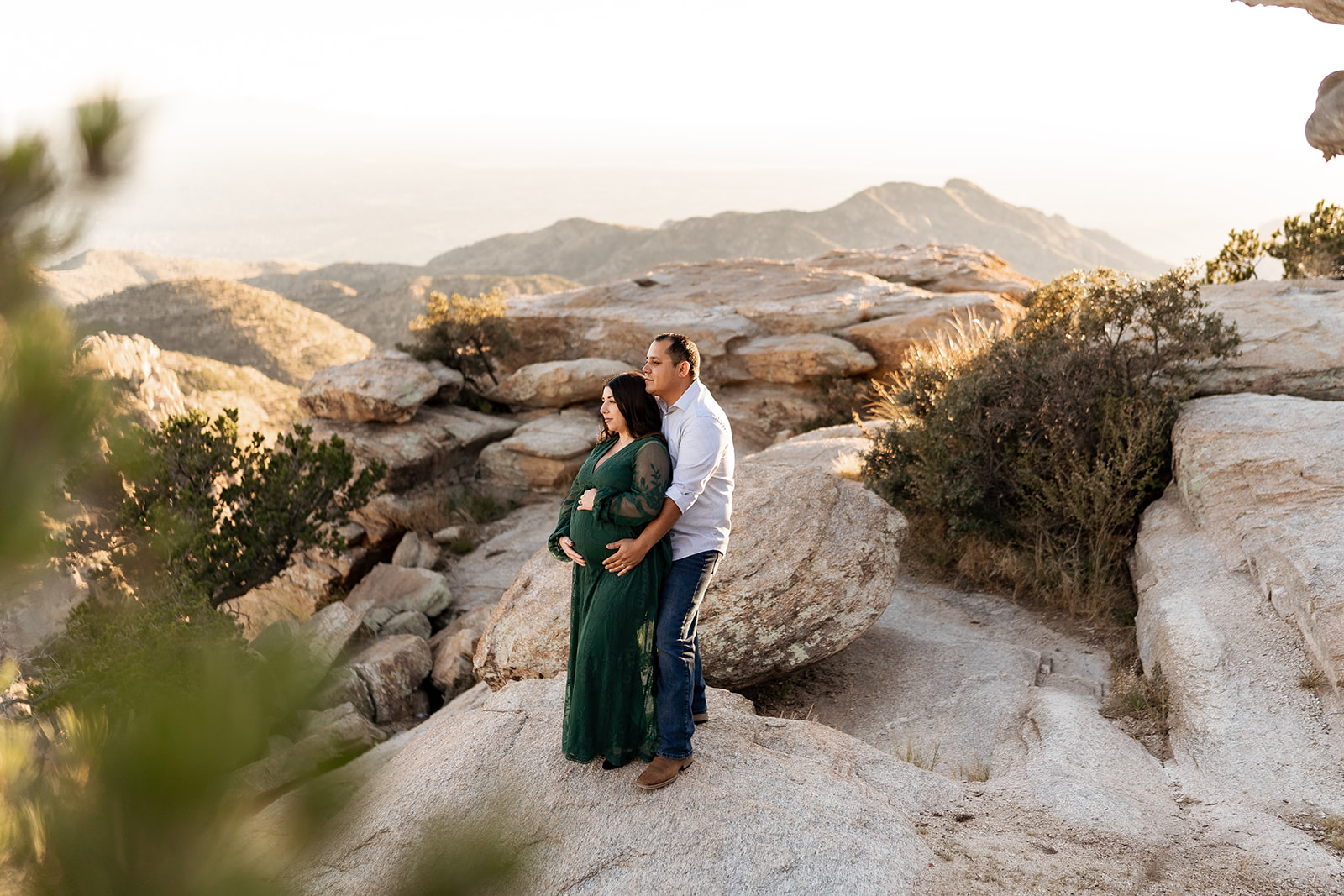a couple posing for maternity photos at Windy Point at Mount Lemmon