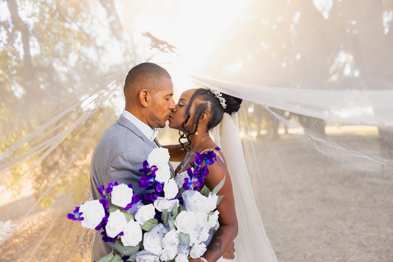 a couple who is kissing under the veil and posed for their post wedding couples portrait session  