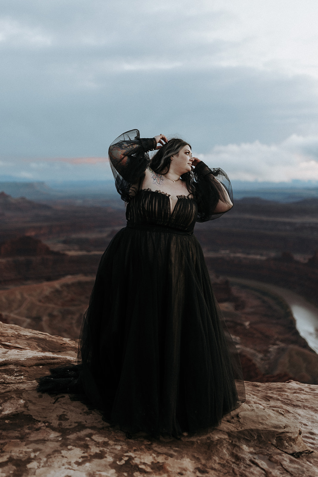A bride in a black wedding dress with a canyon at Dead Horse Point in the background.