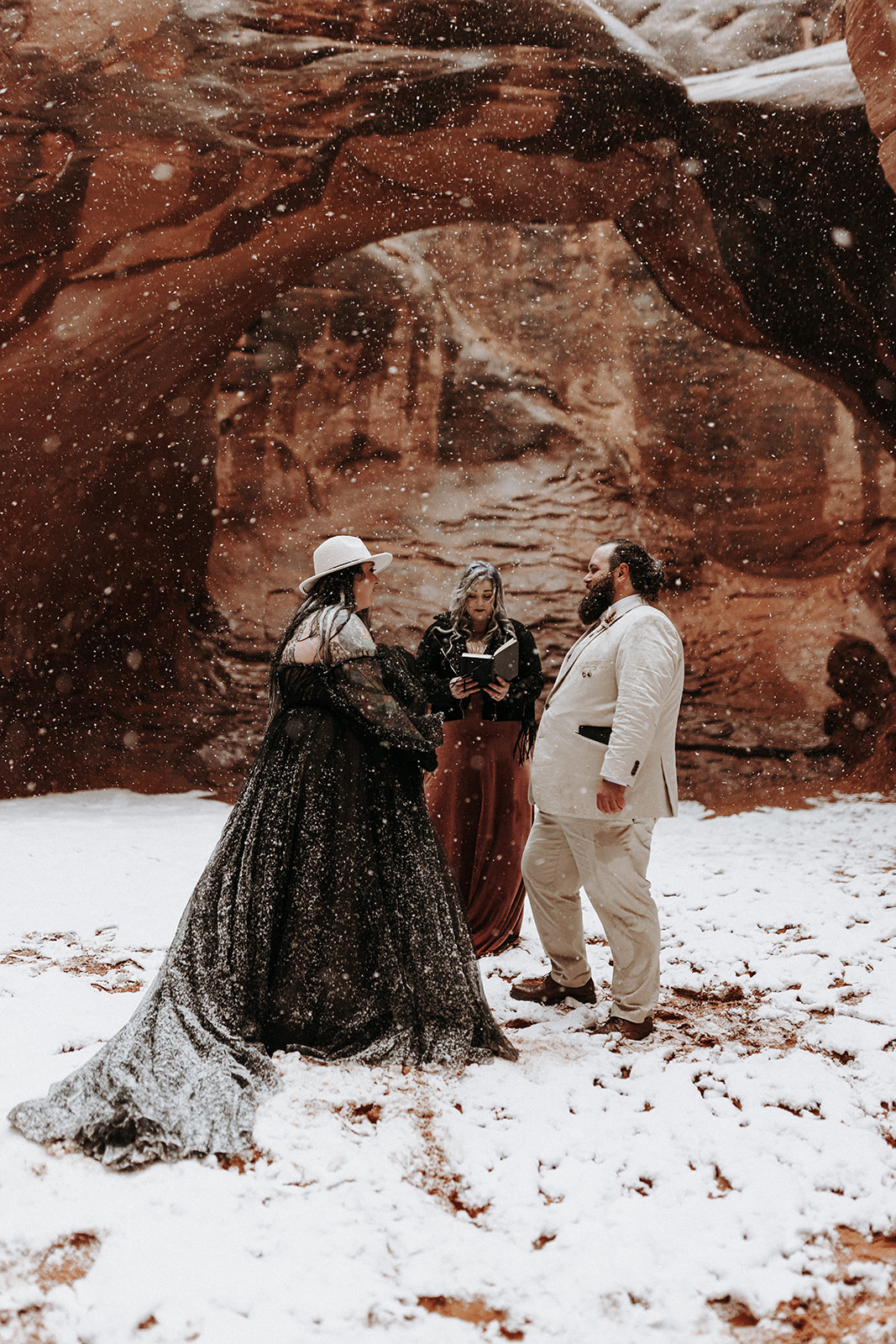 A snowy boho winter wedding ceremony at Sand Dune Arch in Arches National Park.