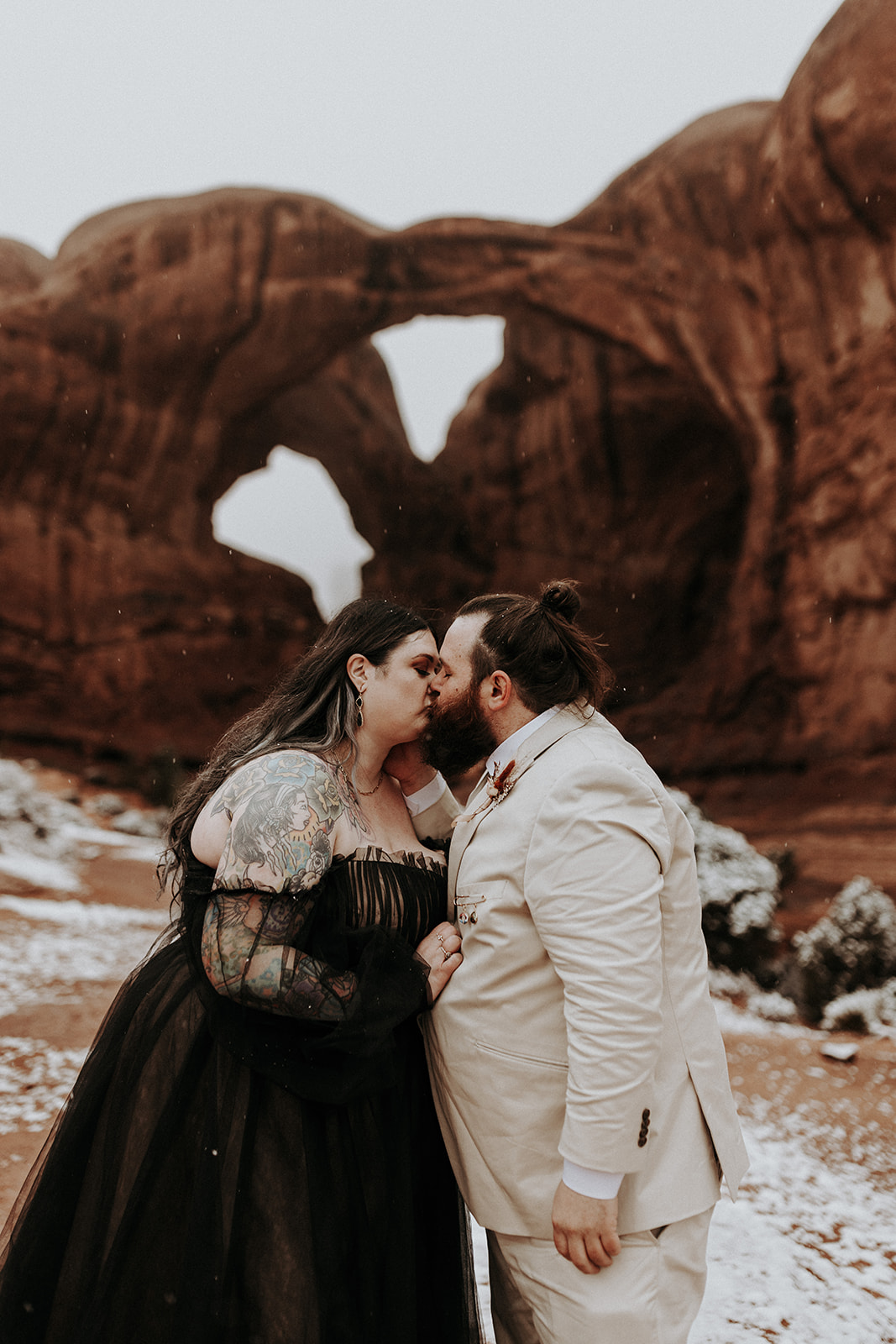 A plus size wedding couple kissing in front of Double Arch in Arches National Park, Utah.