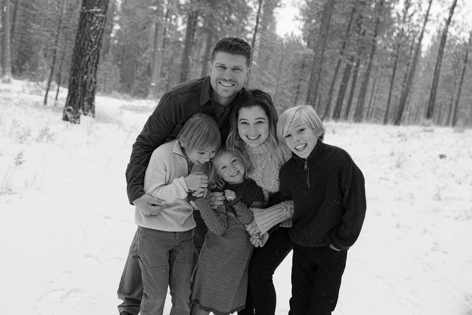 black and white image of a family laughing in a snowy setting in Bend, Oregon
