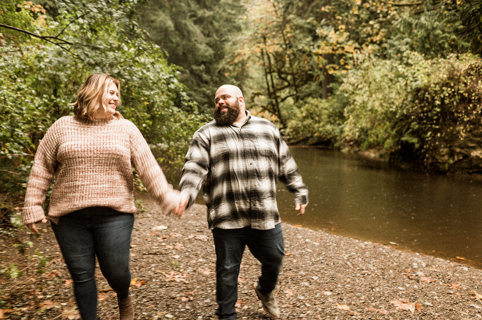 engaged couple walks along creek in oregon holding hands