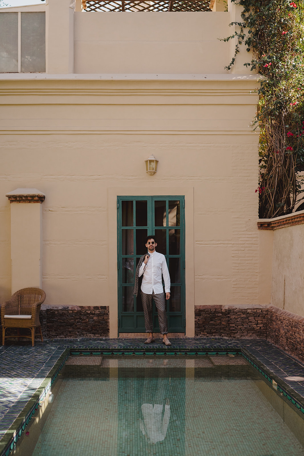 Groom stands by a swimming pool in gardens of Les Deux Tour during his elopement in Marrakech