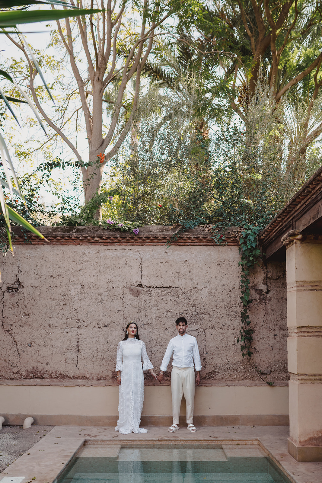 A couple who eloped in Marrakech stand by the pool in Les Deux Tours hotel