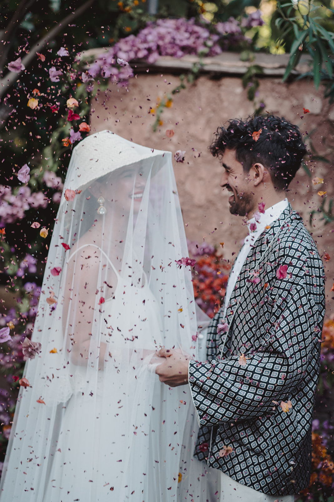 A couple who eloped in Marrakech walk through confetti tunnel in the gardens of Les Deux Tours hotel