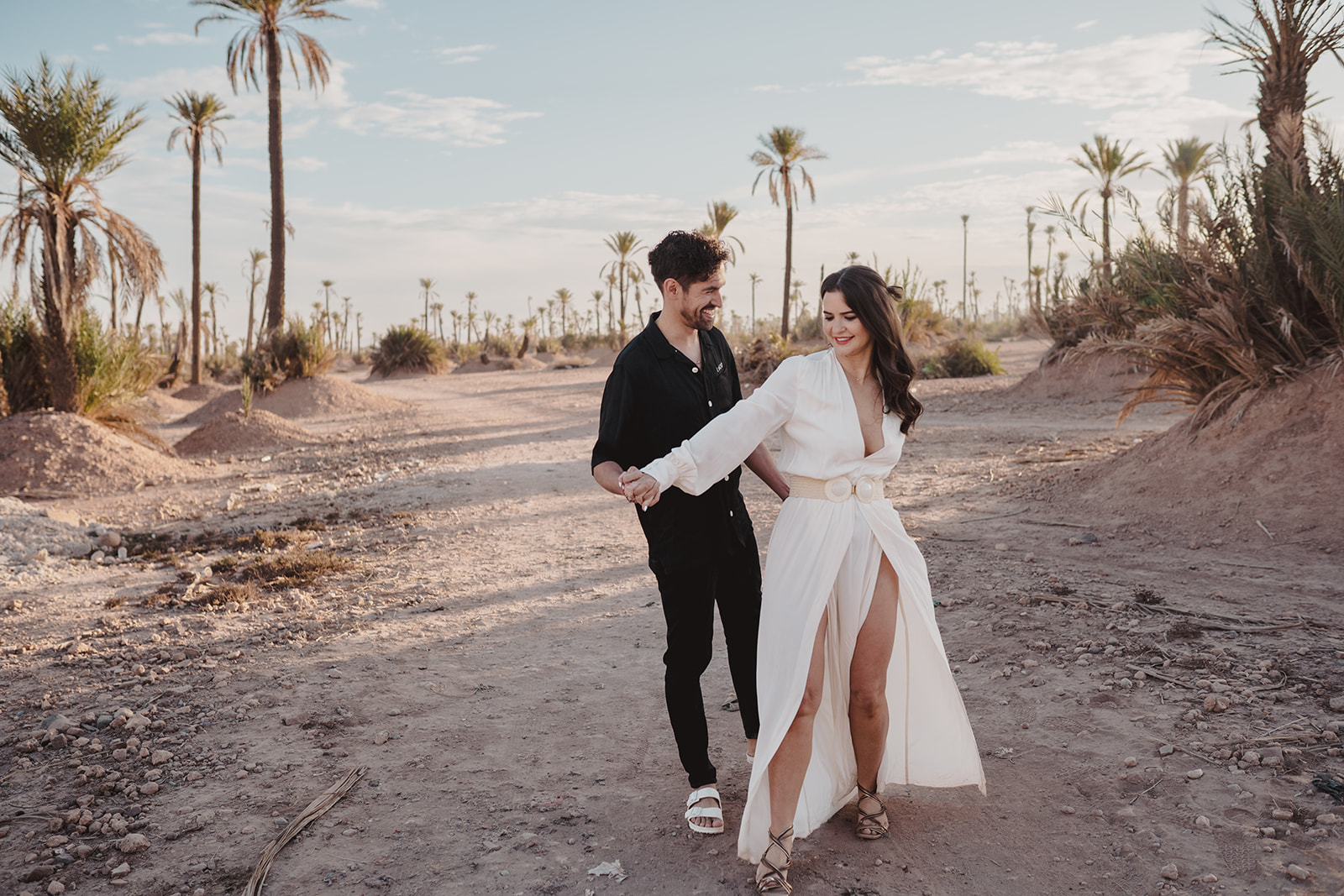 A couple who eloped in Marrakech walk in the Moroccan dessert at sunrise