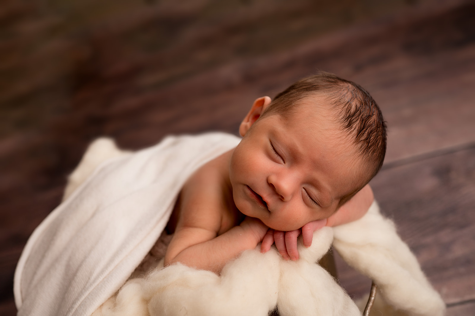 close up of newborn baby girls face posed in a bucket for studio photography