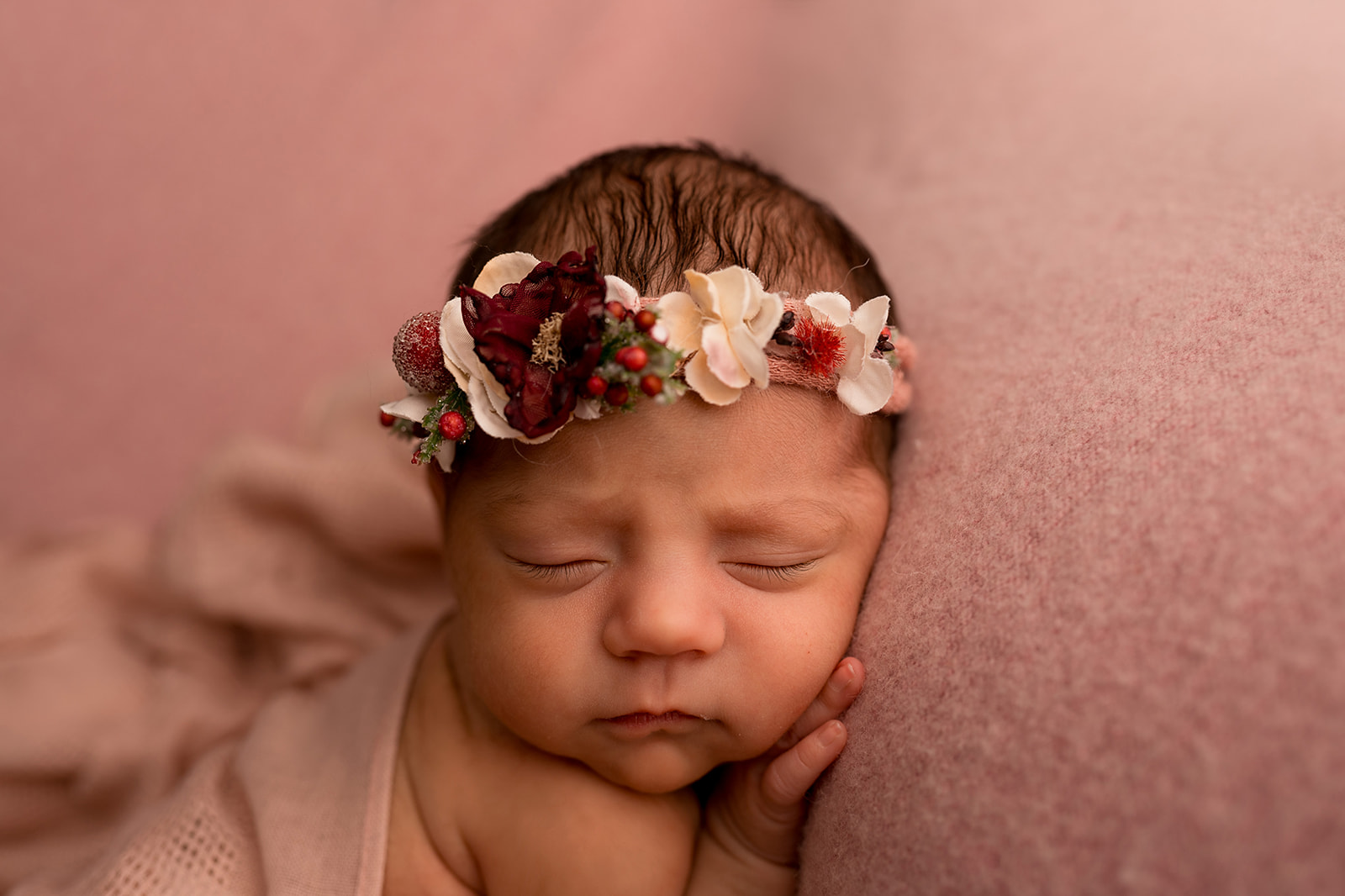 Studio newborn posed picture of baby girl with pink backdrop and floral background