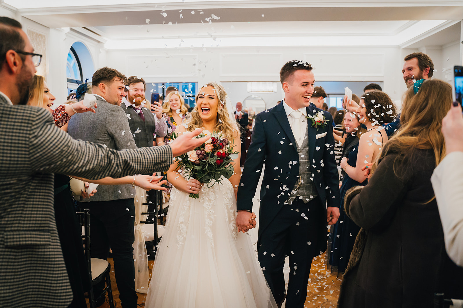 guests throw confetti over the newly-weds