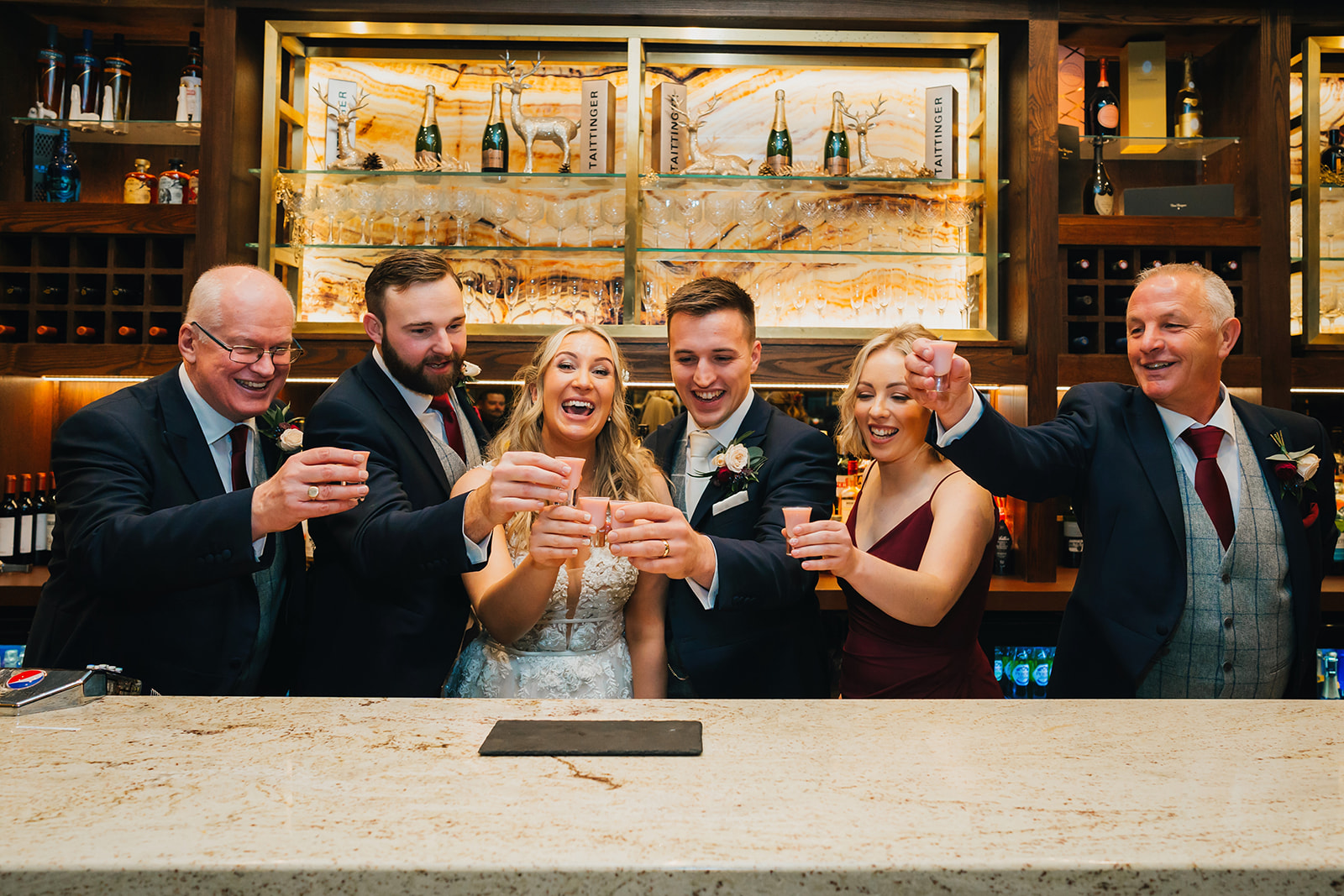 the bride, groom and their loved ones share a toast behind the bar