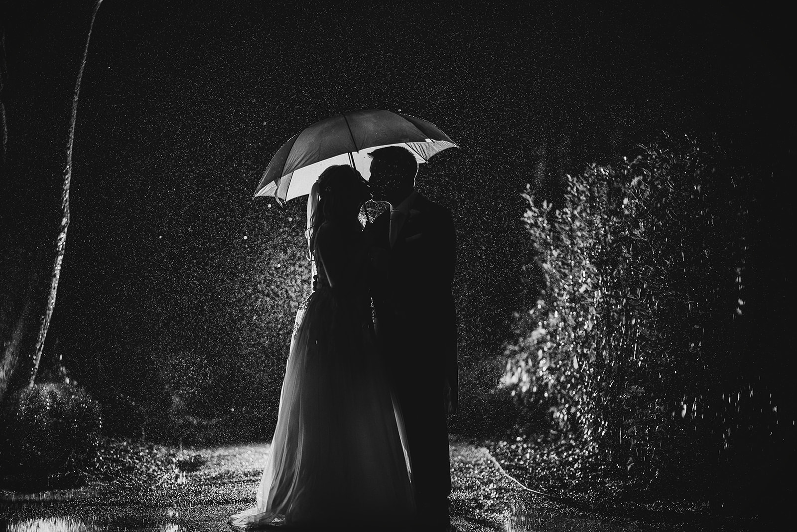 a black and white night portrait of ht bride and groom, lit with an off-camera flashgun behind