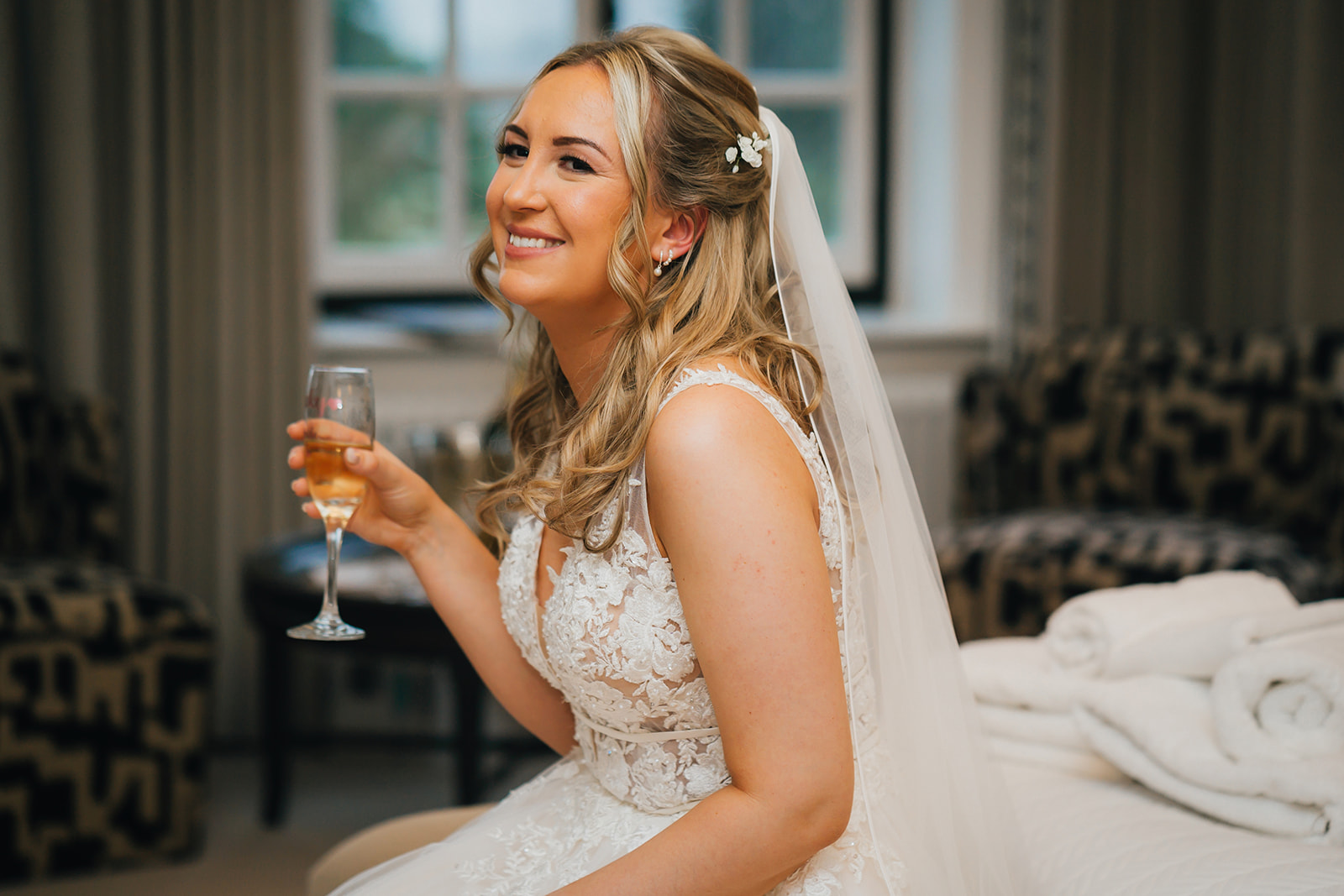 the bride laughs as she drinks champagne in the bridal suite