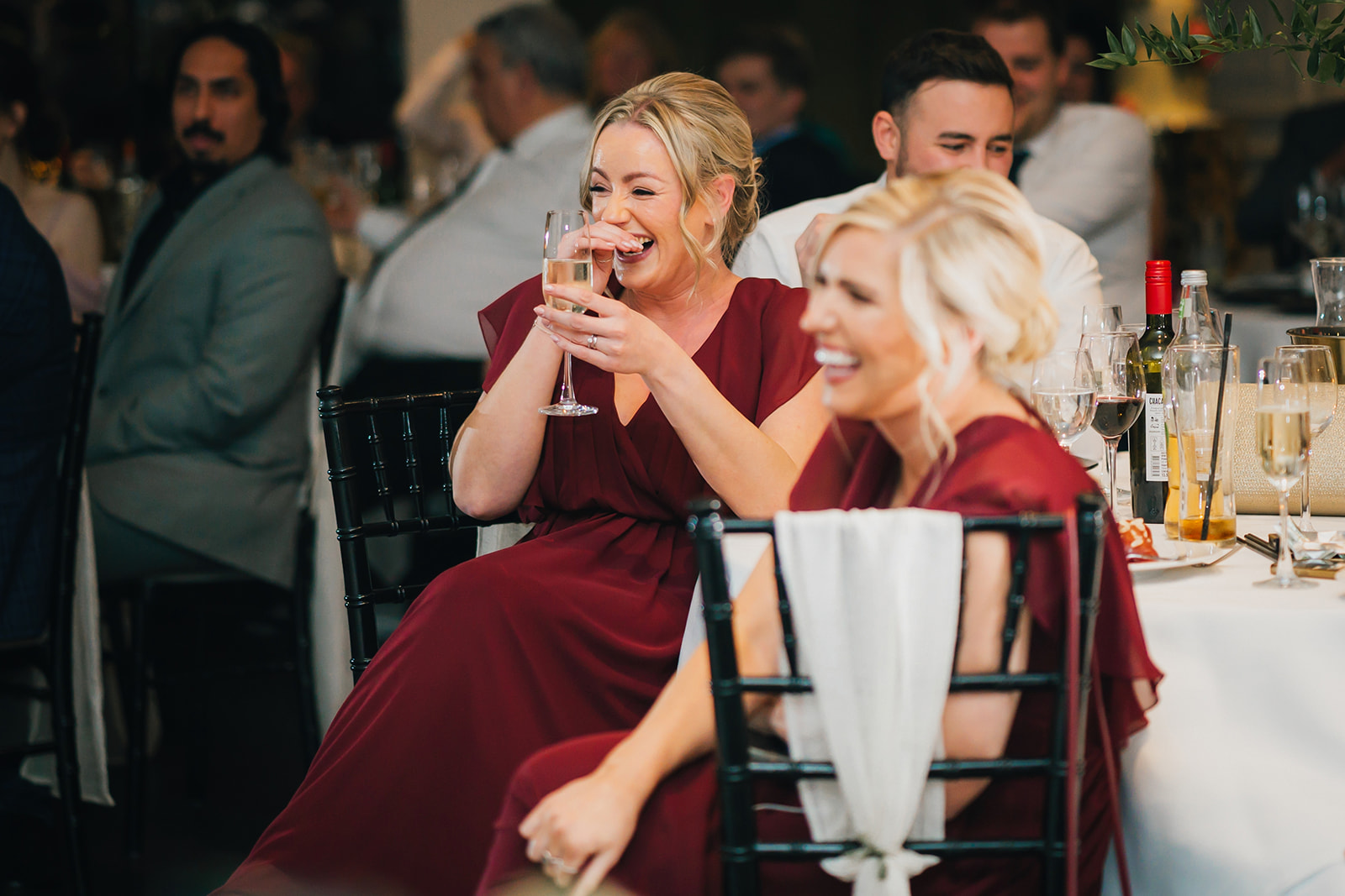 two bridesmaids laugh as the listen to the wedding speeches
