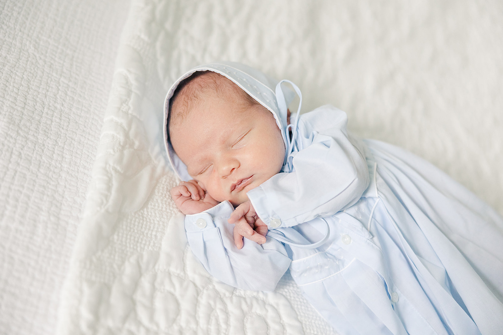 Blue and white newborn boy in bonnet photos at home