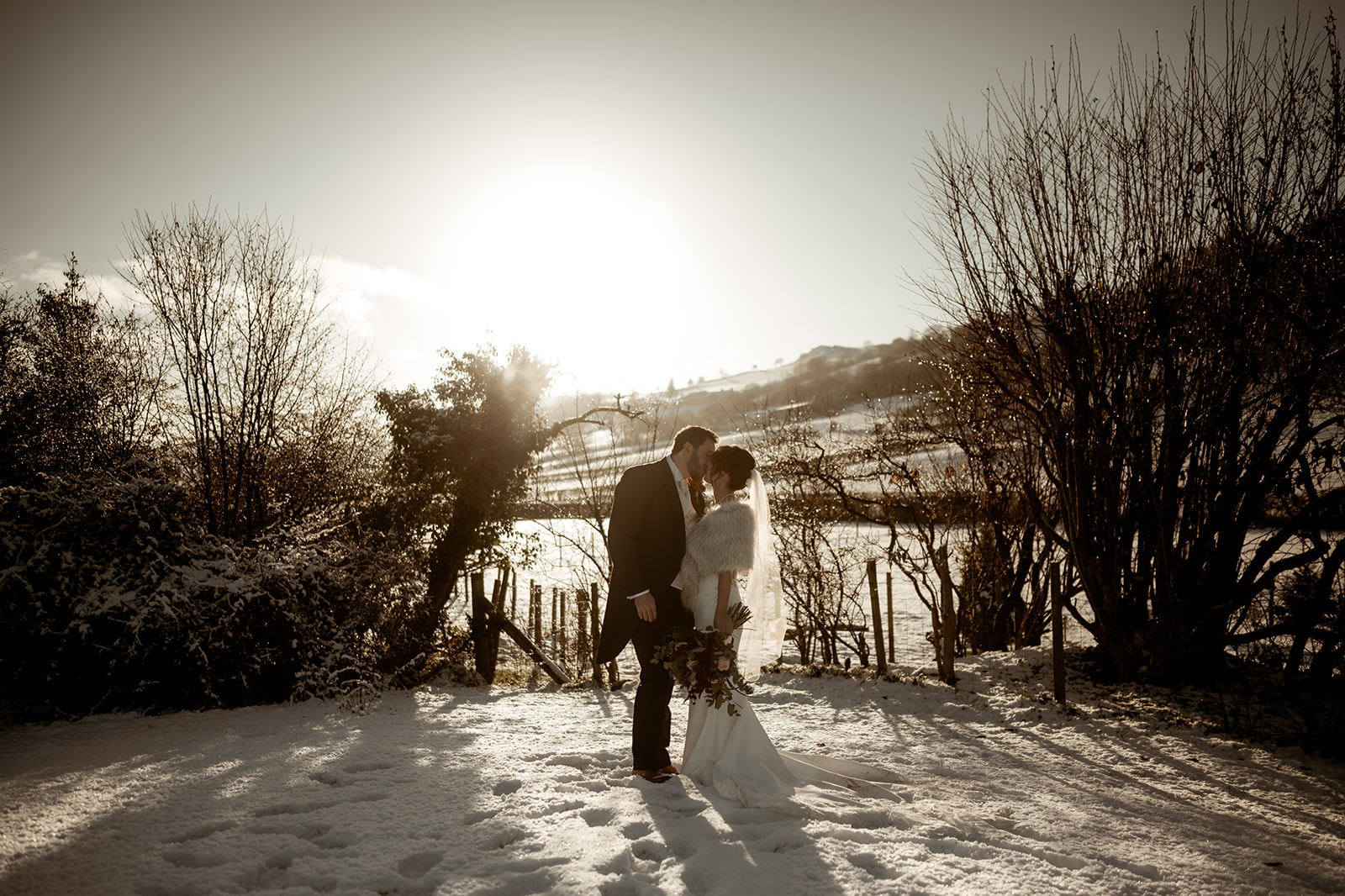 A couple kissing in the snow after getting married at The Gwenfrewi Project