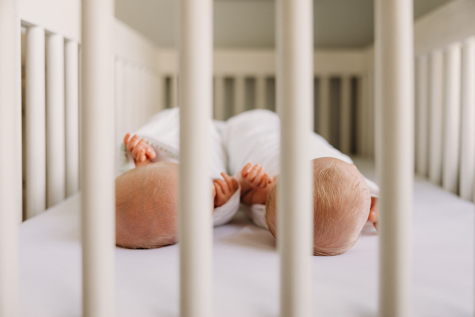 Photo of twins laying in a crib.