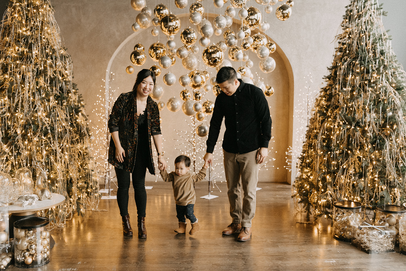 Parents walking with their toddler son in Mintroom studio decorated with golden ornaments