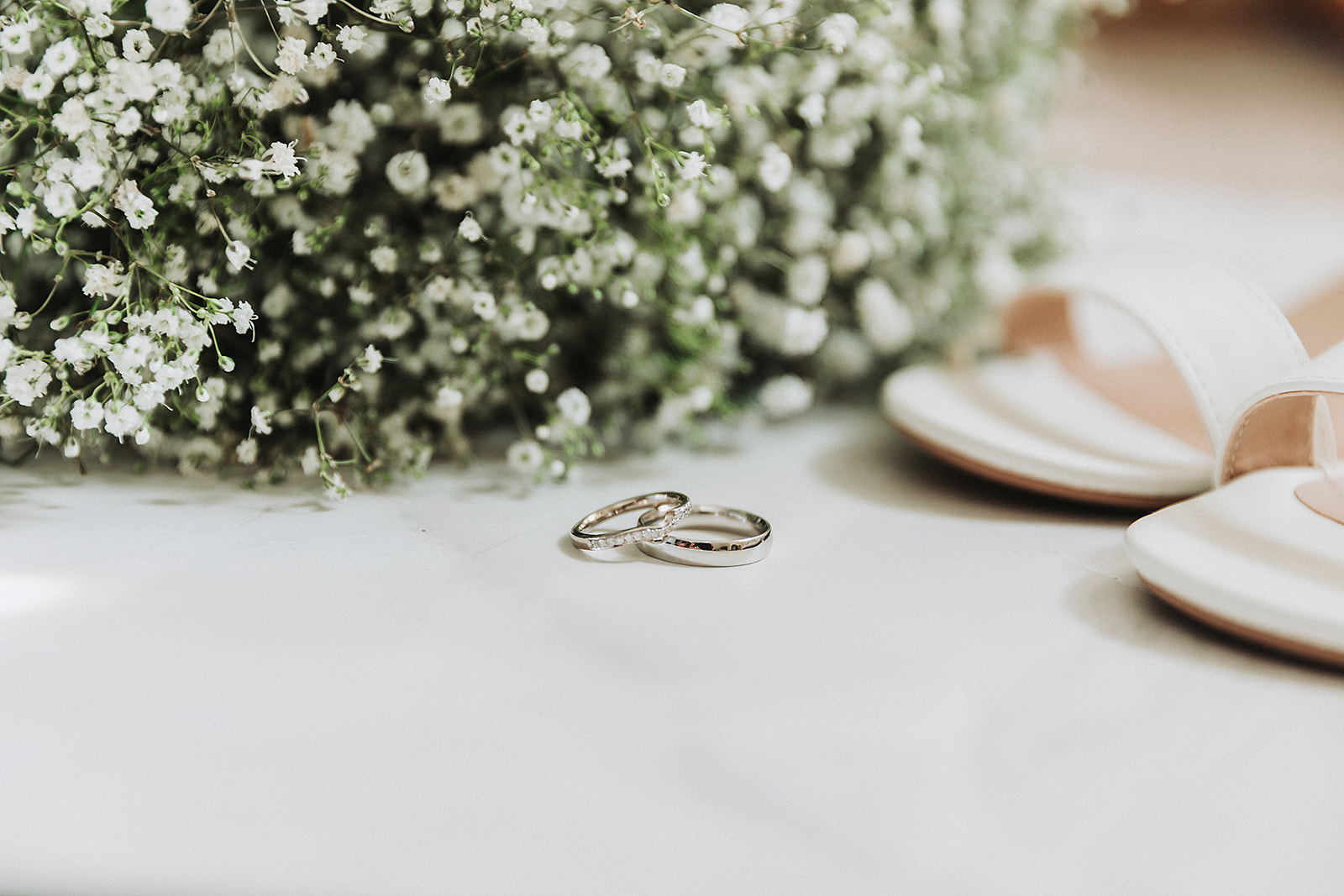 Wedding Rings, laying infront of wedding flowers and wedding shoes. Photo by Perfect Memories Photography