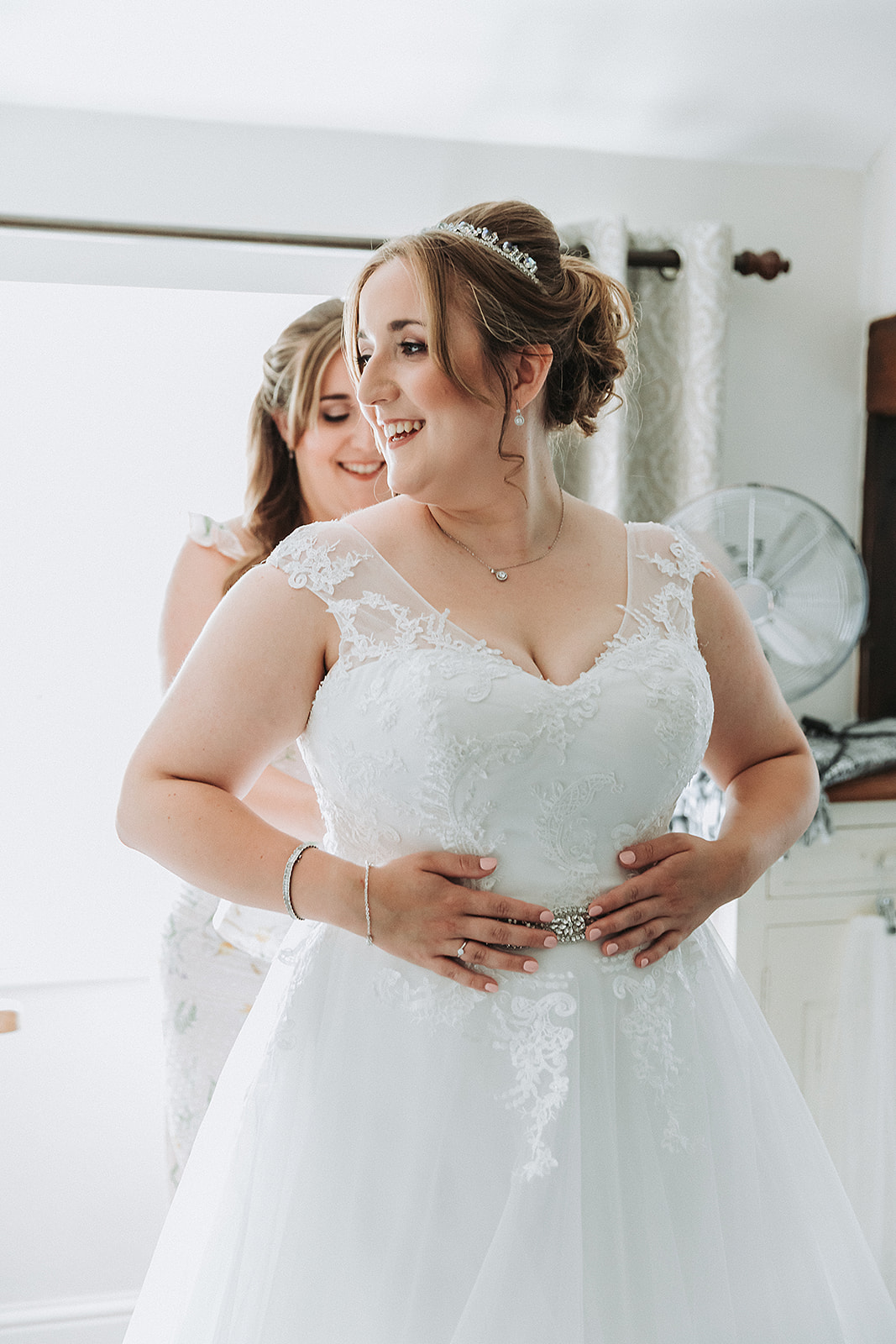 bride having her dress done up by her sister. Wedding Photo by Perfect Memories Photography