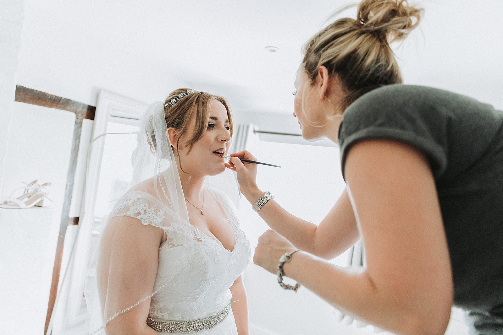 Bride getting ready with her make up artist in her wedding dress and veil. Wedding Photo by Perfect Memories Photography