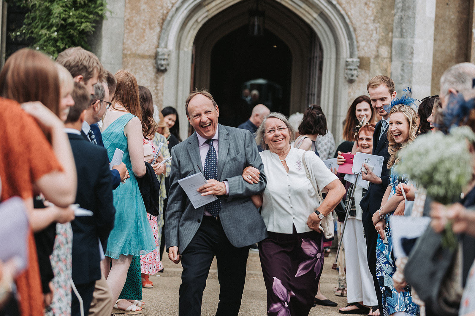 Wedding guests walking in-between wedding party at little gaddesden church Hertfordshire.