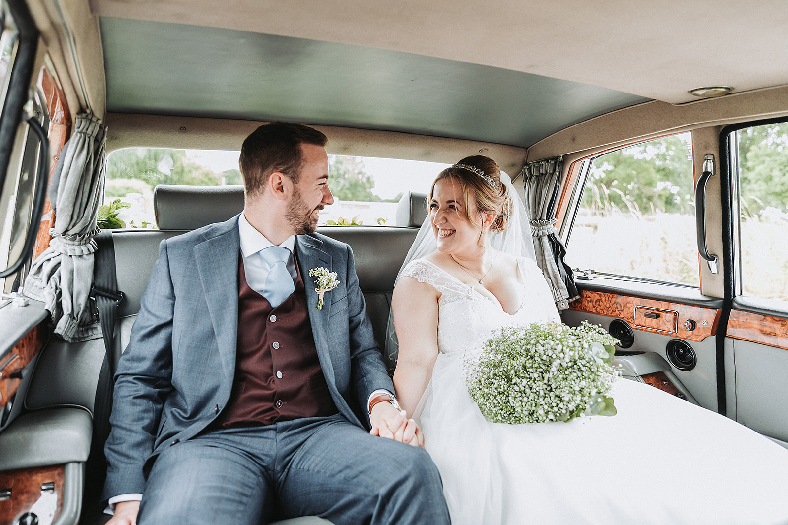 Bride and groom sitting and smiling inside the car from Lord Cars London. Wedding photo by Perfect Memories Photography