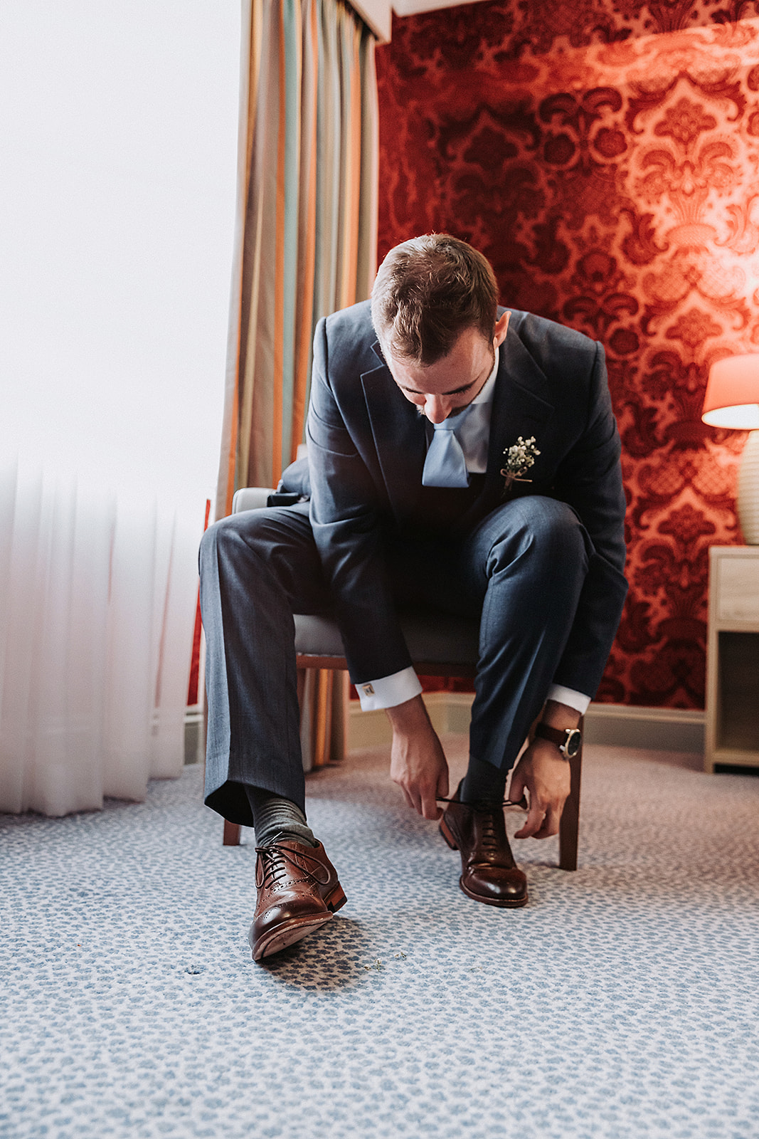Groom putting on his wedding shoes in his suit at Pendley Manor, Tring. Wedding Photo by Perfect Memories Photography