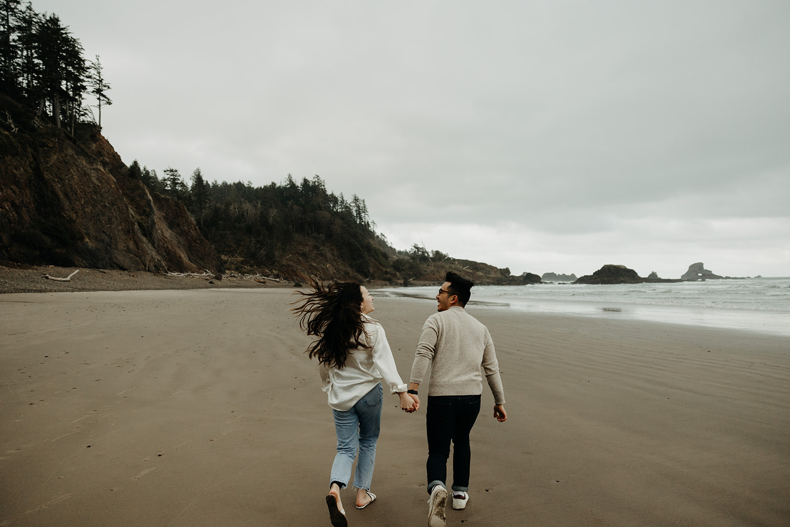 A couple holding hands on the beach in Ecola State Park at the Oregon Coast