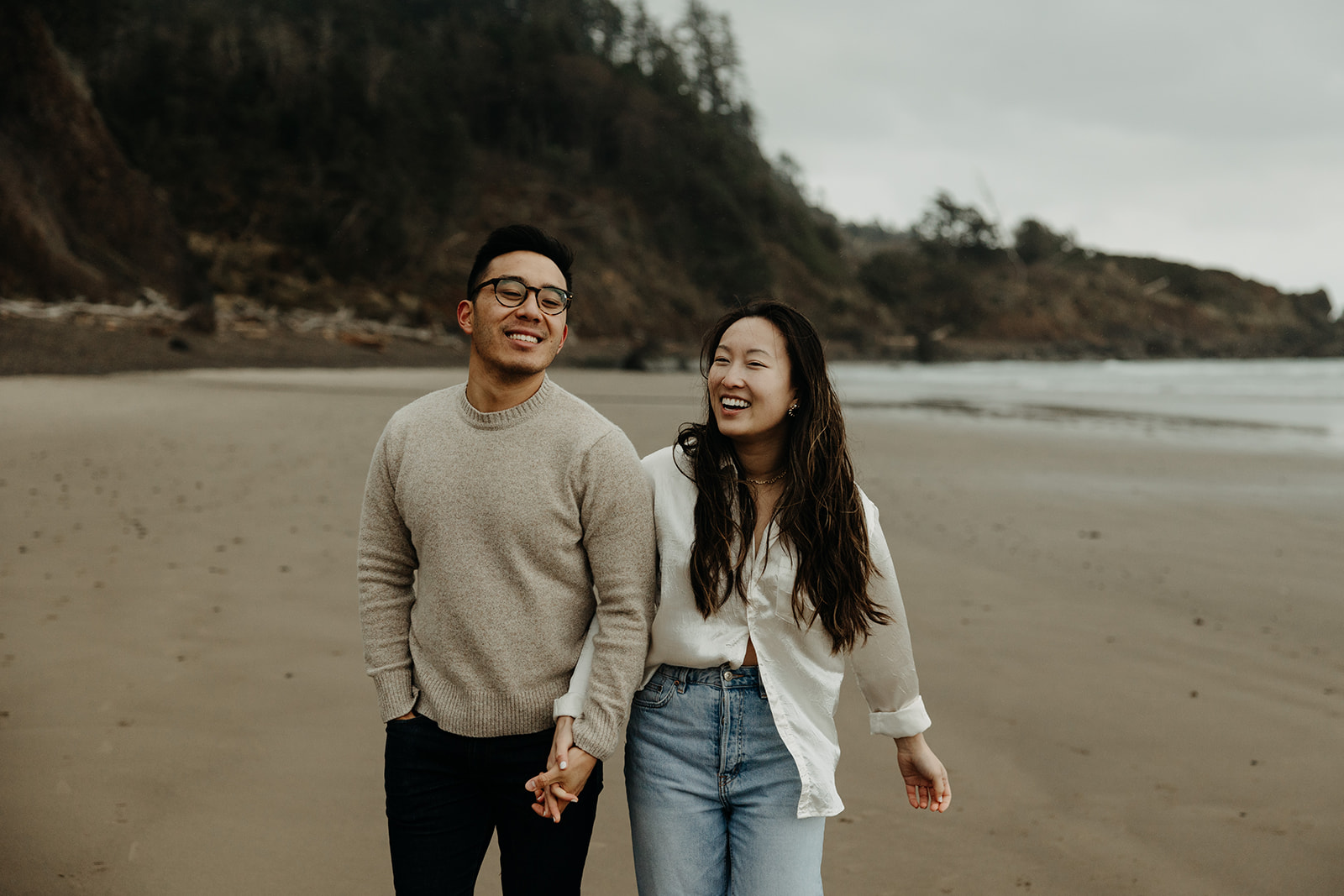 A couple holding hands on the beach in Ecola State Park at the Oregon Coast